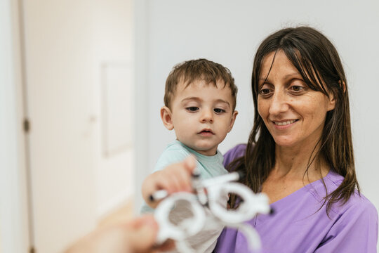 Optometrist holding trial frame in front of baby boy during eyesight testing