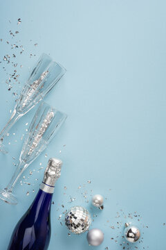 Happy New Year 2027 celebration with champagne bottle, flutes, confetti and silver ornaments on blue vertical background