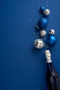 Happy New Year 2027 celebration with blue and silver ornaments, confetti and champagne bottle on vertical blue background