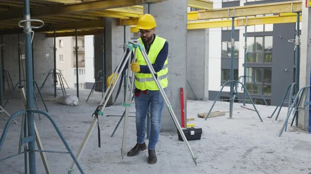 Surveyor setting up theodolite on construction site
