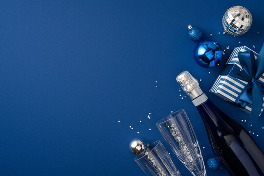 Happy New Year 2027 celebration with blue champagne, glasses, ornaments and wrapped gift on winter background
