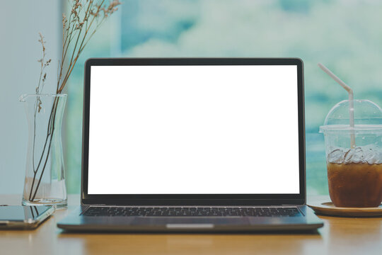 Mockup of laptop computer with empty screen with coffee and smartphone isolate on wooden office desk in coffee shop like the background ,White screen