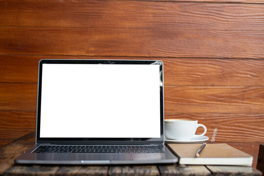 Mockup of laptop computer with empty screen with coffee cup and smartphone on table of tree branch shadow the cafe coffee shop background,White screen