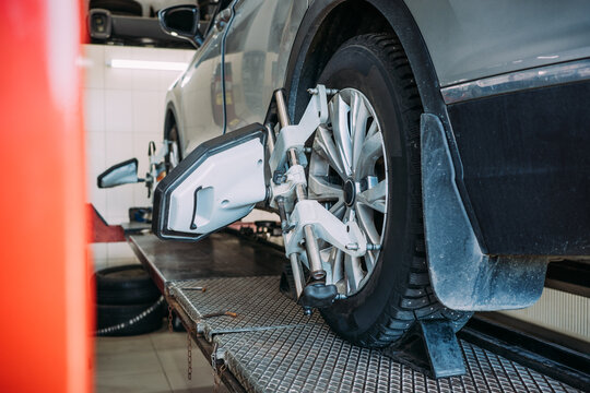 Wheel alignment car service repair maintenance workshop concept, showing alignment equipment mounted on tire for suspension, steering geometry and safety calibration.