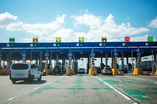 Highway toll plaza road traffic transportation infrastructure travel concept, showing cars entering controlled lanes with booths, signals and payment checkpoint.
