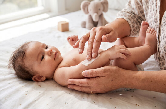 Parent applying moisturizing cream on baby arm during daily care routine