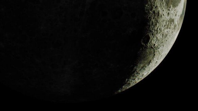 This shows a close view of the moon in a crescent phase. The surface details are visible, with craters and shadows. The image is captured from Earth at night.
