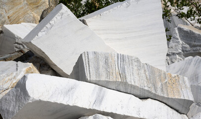 Large raw white marble blocks stacked in a quarry. Unpolished natural stone slabs with grey veining and rough textures. Industrial mining and construction material background © scaliger