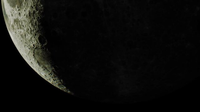 A close view of the moon shows its surface with craters and shadows. The image captures the moon during night time. The dark background highlights the moons details well.