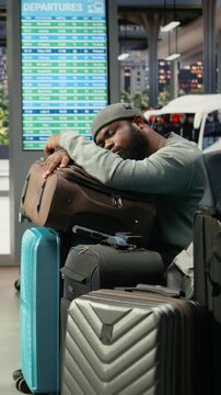 Vertical frame: Close-up of weary traveler dozing on trolley in bus terminal