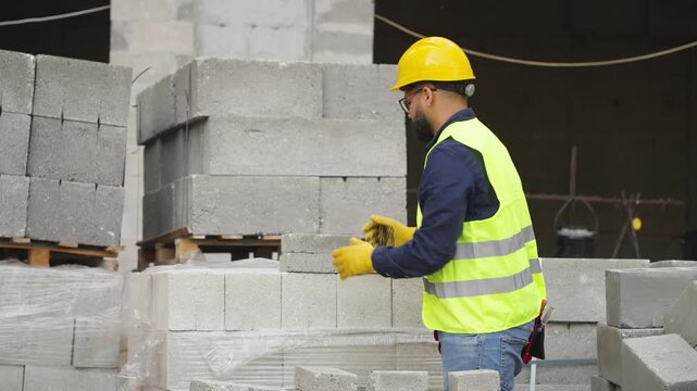 Construction worker stacking concrete blocks at building site