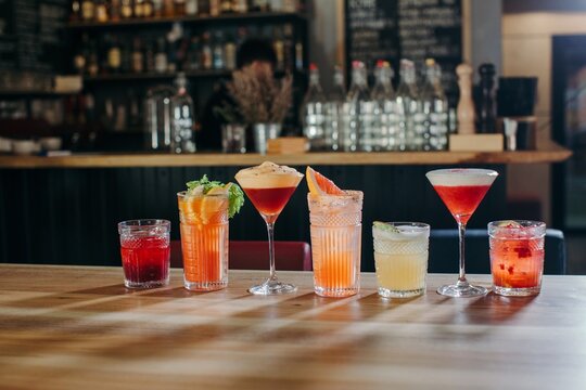 Row of assorted cocktails on a wooden table in a bar