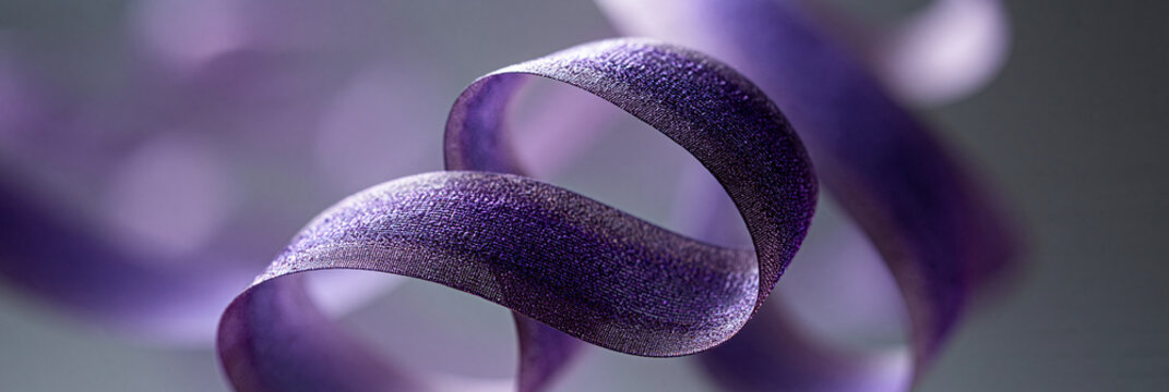 A delicate purple ribbon gracefully twists against a soft backdrop.