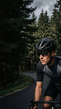 Cyclist riding bicycle on asphalt road in forest. Professional athlete training for road cycling race. Active man enjoying speed and cardio exercise outdoor. Healthy lifestyle concept.