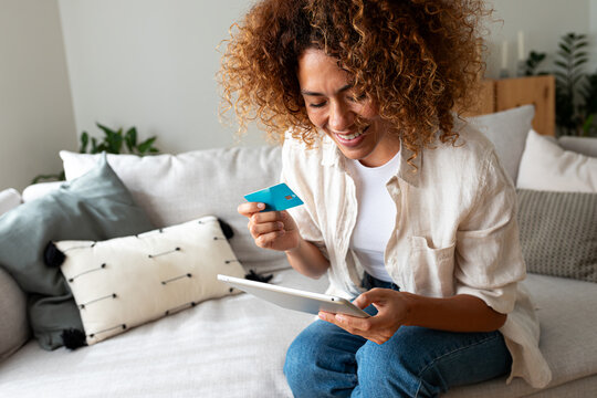 Woman online shopping at home using tablet and credit card