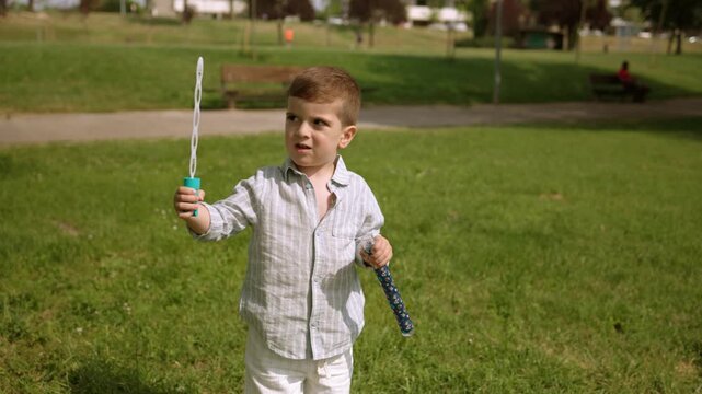Little boy creating and playing with soap bubbles in the park