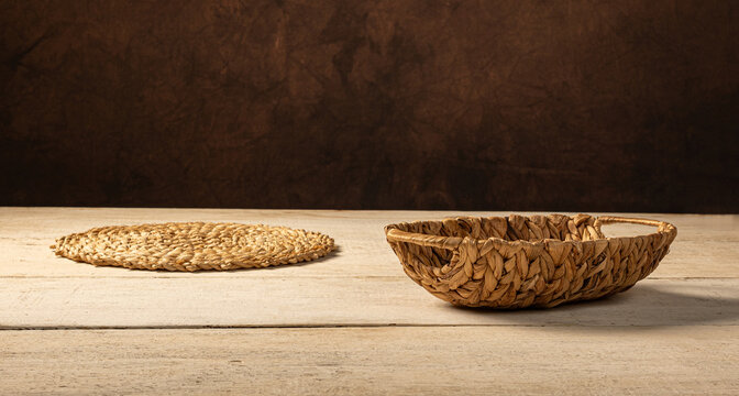 Straw basket,  a beautiful straw basket and straw mat, empty on a rustic white wooden surface, with an abstract dark background and selective focus.