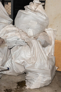 Stacked polypropylene bags filled with construction debris and demolition waste. Direct lighting and sharp focus on work textures for stock.