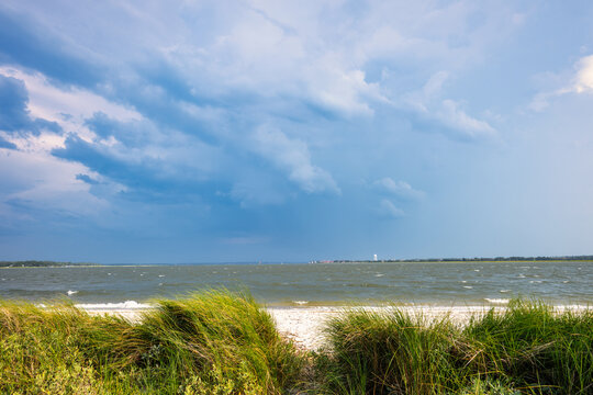 Cloudy skies over a beach with grass in the foreground and parris island  in the background