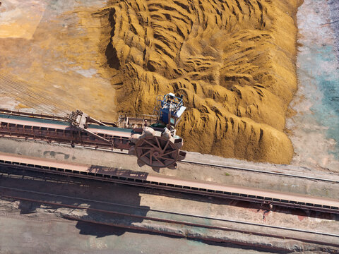 Bucket Wheel Reclaimer Moving Material at a Mining Facility During a Sunny Day With Large Dirt Piles