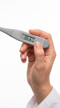 A close-up shot of a person holding a digital thermometer displaying a normal temperature of 36.6&deg;C