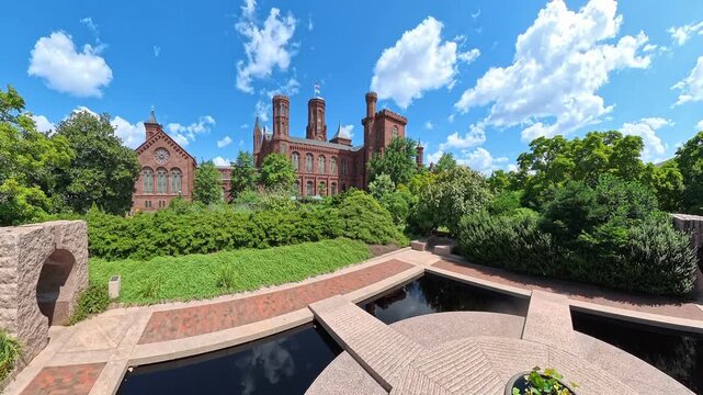 Camera glides above a geometric pond toward Smithsonian Castle in Washington DC.

