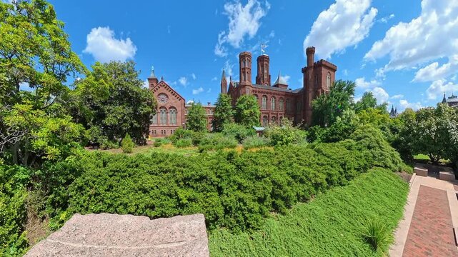 Sunny garden panorama frames the Smithsonian Institution Building beneath dramatic clouds.
