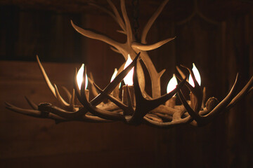 Illuminated Rustic Antler Chandelier Hanging in Warmly Lit Cabin Interior © Unstaged Stock