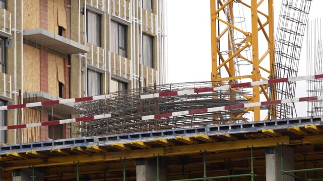 Construction site showing tower crane, building facade installation and structural development, capturing modern urban construction processes, engineering work and real estate growth
