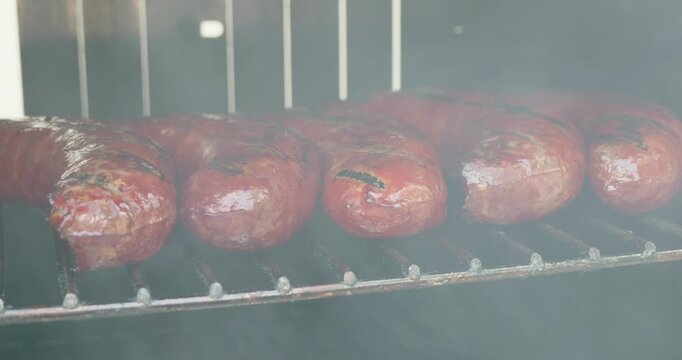 Panning view of smoked sausages cooking inside a smoker grill