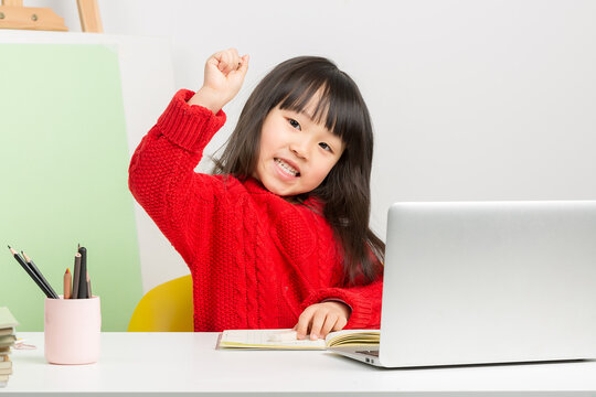 Intelligent Chinese girl doing homework at desk, thinking deeply and having a great idea or eureka moment.