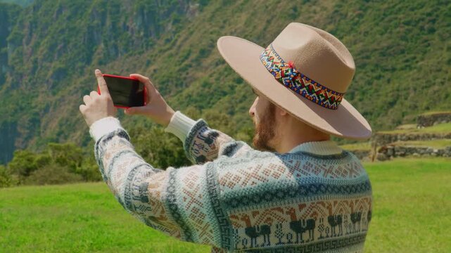 Adult man holding smartphone horizontally to take a picture of mountain landscape, photography concept