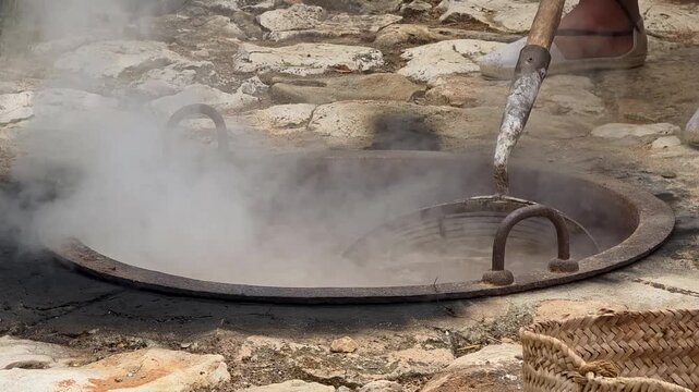 Smooth camera zoom out from close up scalding grapes to wide view of reed drying racks canyissos during traditional escalda process.