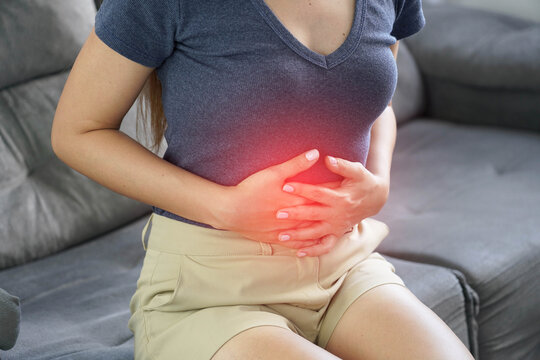 Close Up of Young Woman Clutching Her Abdomen Suffering from Stomach Cramps and Gastritis