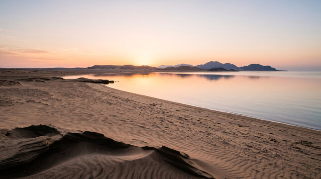 Plage d&eacute;sertique paisible au coucher du soleil avec montagnes &agrave; l'horizon