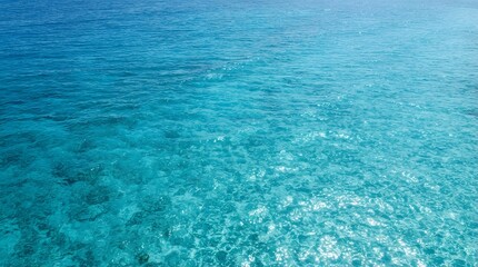 Obraz premium Aerial view of clear turquoise ocean water surface with sun glint and gentle ripples