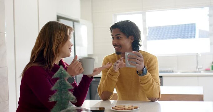 Talking first, mother and son raising mugs, clinking then sipping at kitchen island with cookies