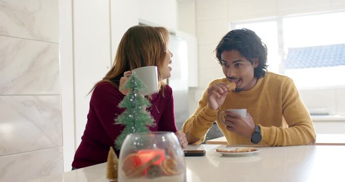 Sipping coffee while glancing at each other, couple chatting and eating cookies on kitchen counter