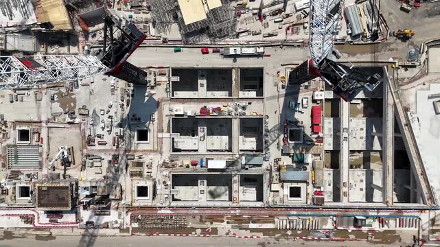 Overhead view of a west London station box under construction showing rows of concrete cells, reinforcement and two large crawler cranes at work