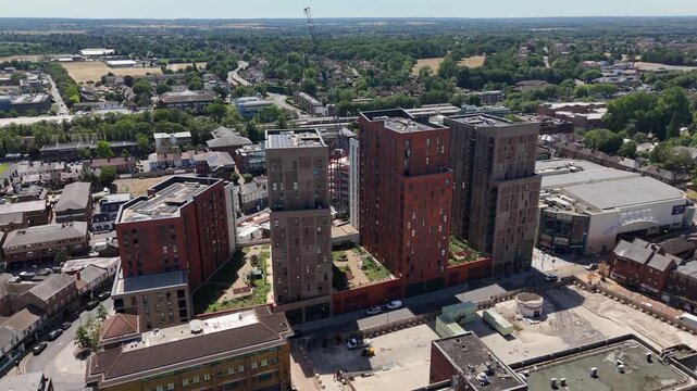 New brick apartment blocks of a residential development stand at the edge of a town, with fields and wooded countryside beyond