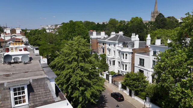 White stucco villas with columned porches stand among mature trees, with a church spire rising on the horizon behind