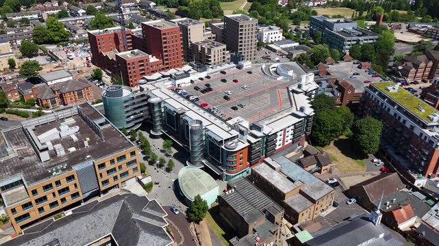 Office building with a rooftop car park and circular glass stair towers stands among the mixed rooftops of a town centre