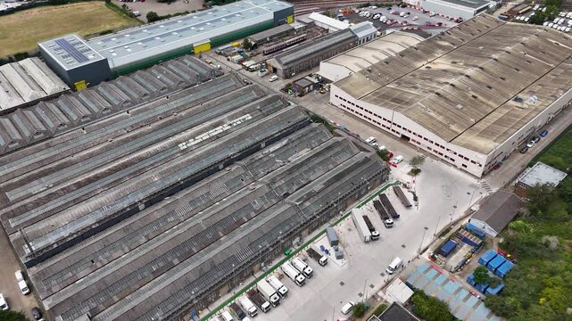 Long saw tooth roofs of a large industrial engineering works with lorries and containers in the yards alongside