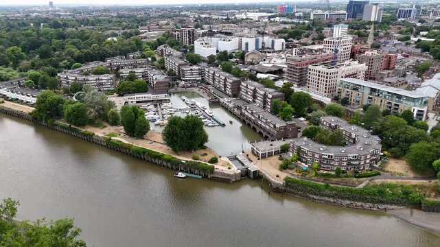 Sheltered marina basin and its waterside apartments seen from across the tidal river at low water