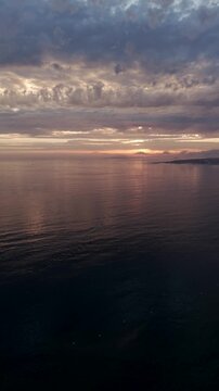 Vertical - Boat crossing calm Atlantic ocean waters at sunset near A Lanzada Galicia Spain