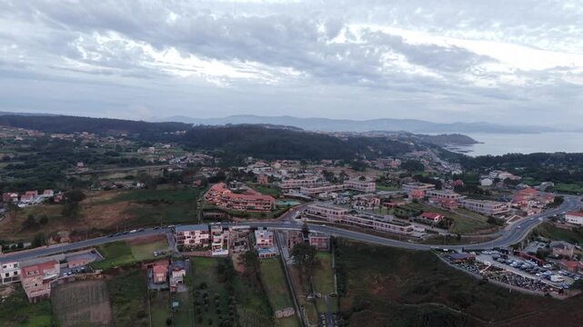 Aerial - Overview of coastal town roads houses and landscape near A Lanzada Galicia Spain