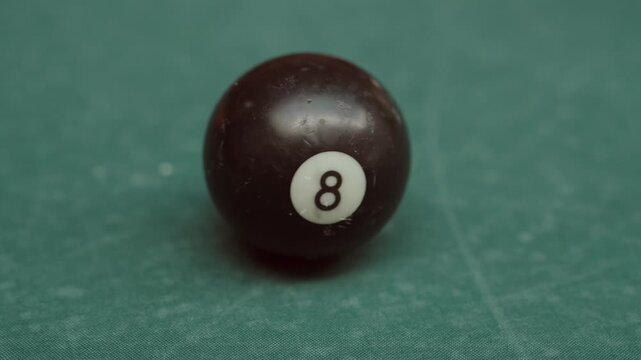 Black 8 ball spinning on green billiard table close