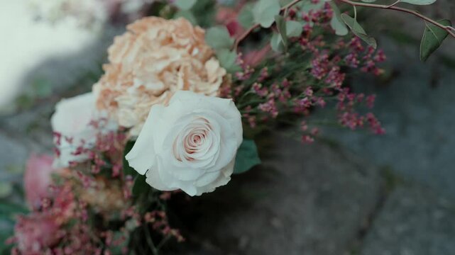 Ivory Rose with Peach Hydrangea Pink Statice and Eucalyptus Laid on a Grey Stone Surface