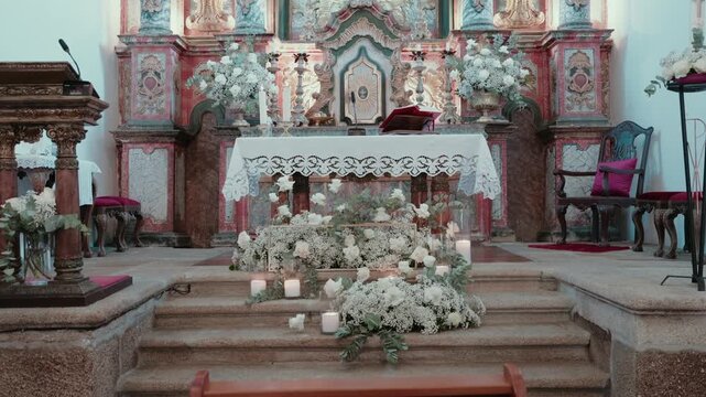 Baroque church altar decorated with white flowers and candles on granite steps