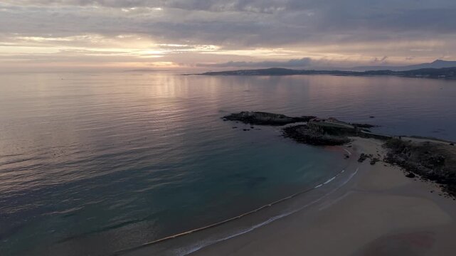Aerial - A Lanzada Beach Bay at Sunset with Turquoise Shallows Sand and Rocky Outcrop